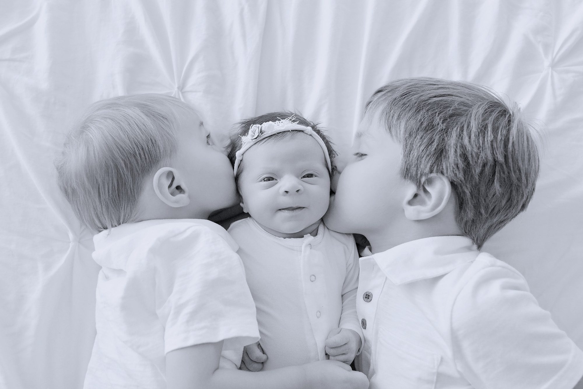 A family fo five getting a newborn portrait in a studio with two boys and the baby is a girl