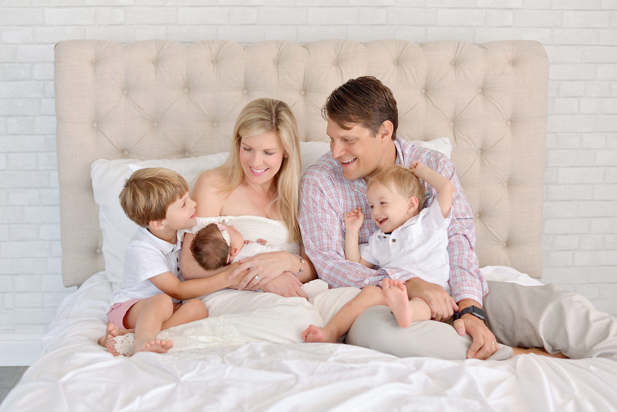 A family fo five getting a newborn portrait in a studio with two boys and the baby is a girl