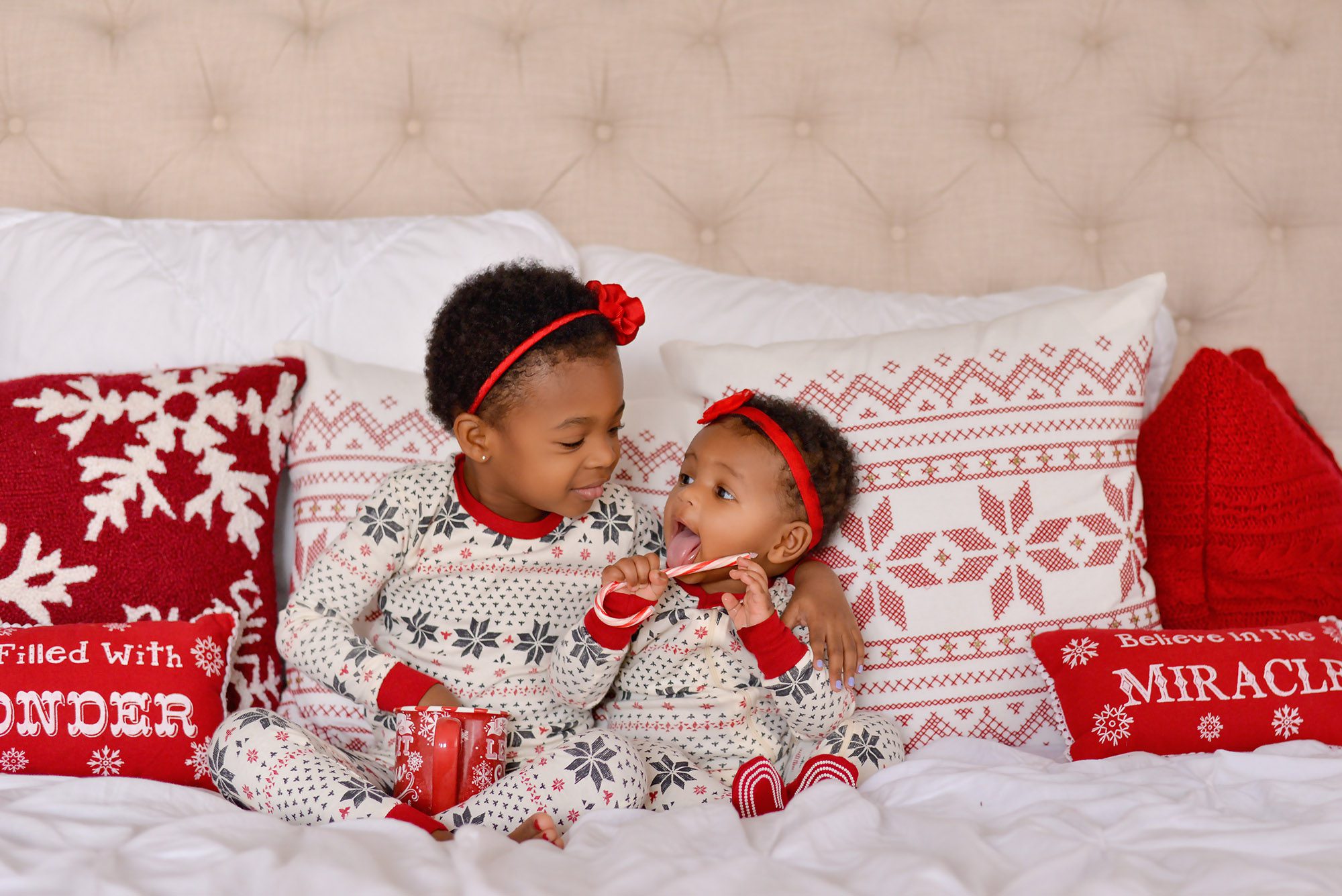 Happy kids dressed up in Christmas pajamas getting photographed in a studio with christmas and holiday decor.