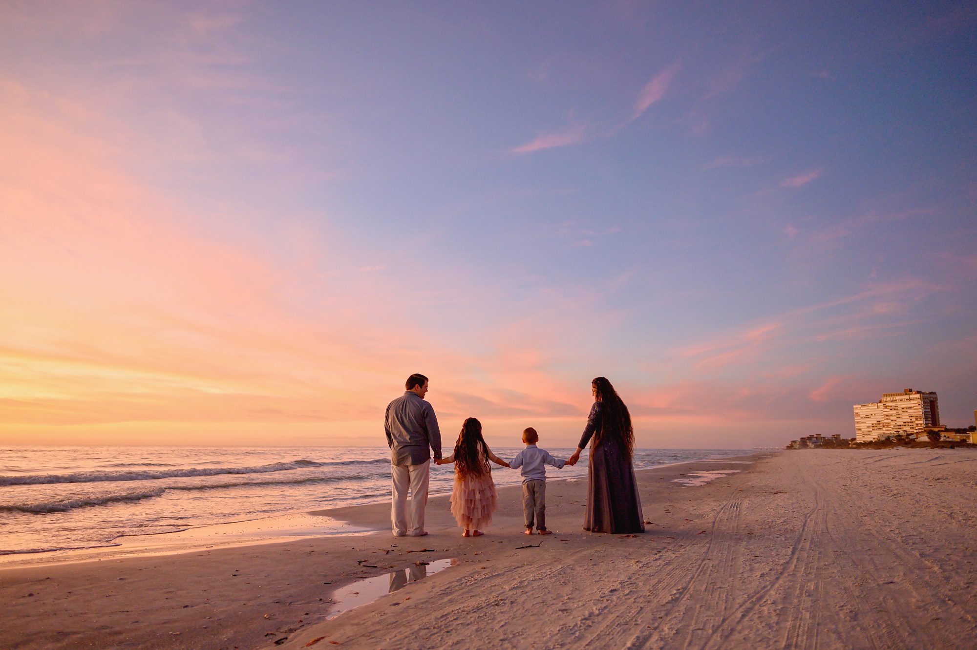 Family of four on vacation in Florida have beach portraits done at sunset.
