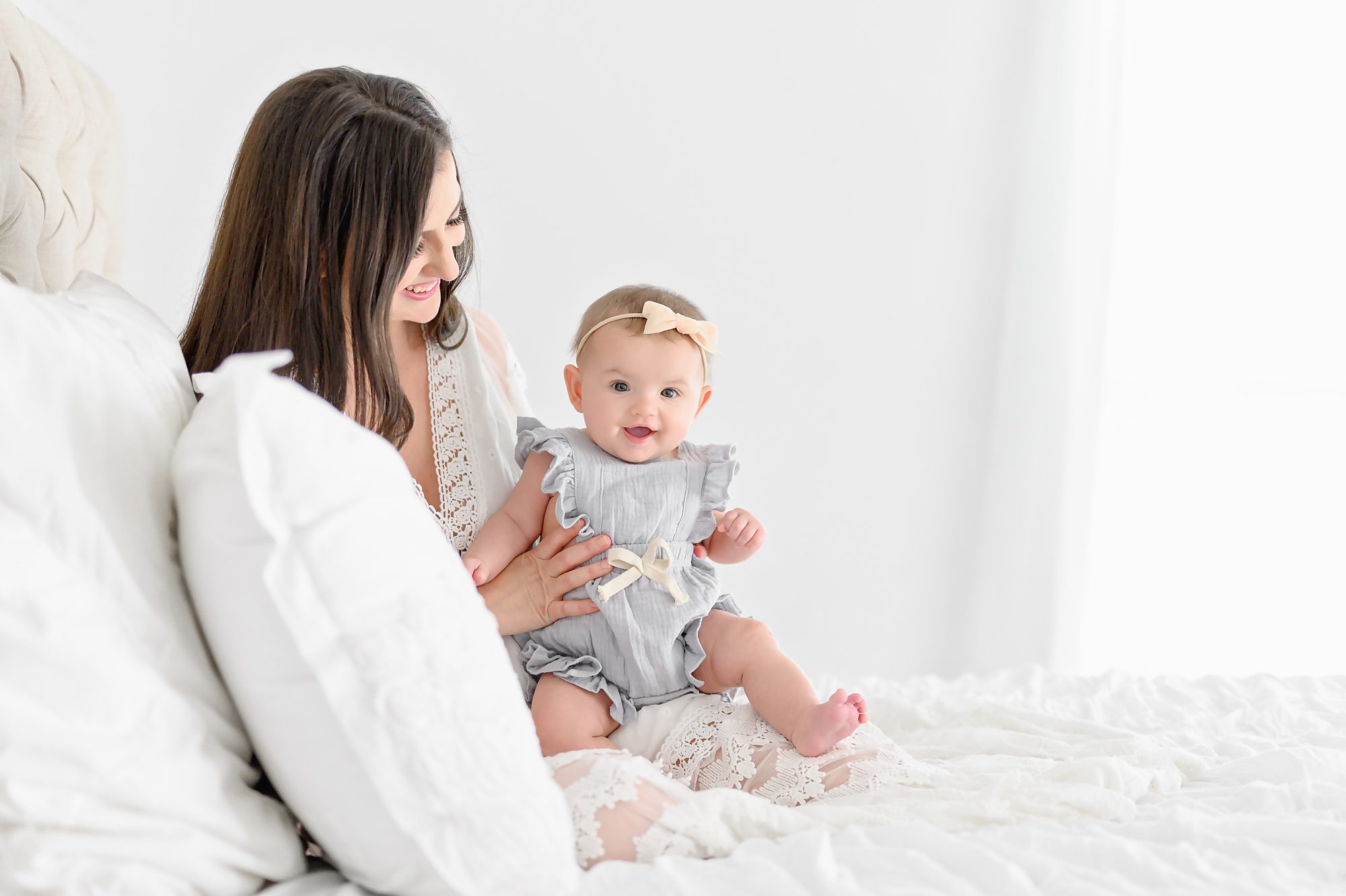 A young brunette mom and her six month old baby girl get mommy and me photos in a bright white studio in Tampa, Florida. 