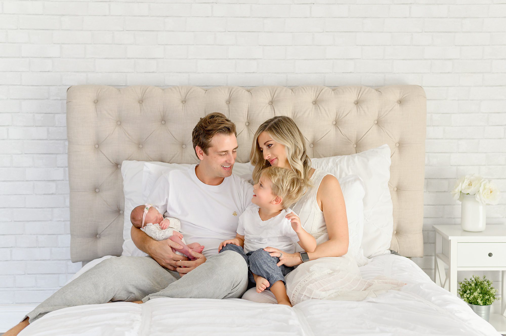 A young family of 4 with a new baby girl gets newborn portraits done in a bright white studio in Tampa Florida.