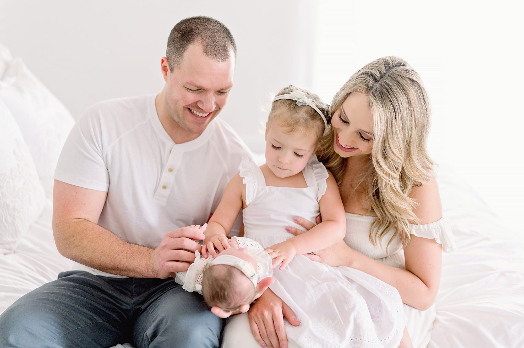 A family of 4 gets natural newborn portraits done in a bright white studio in Denver CO.