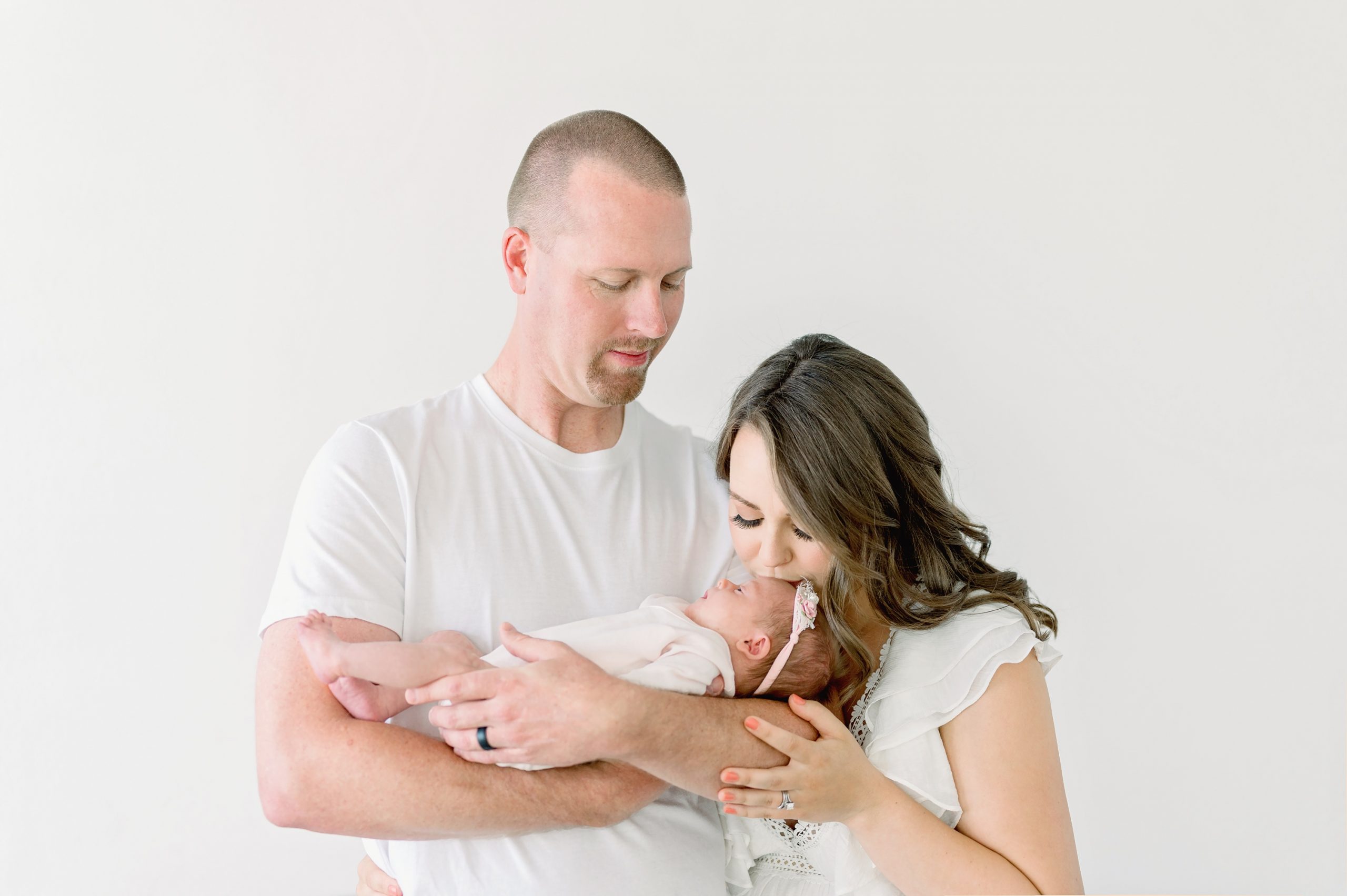 A young couple get fine art newborn portraits done with their new baby girl in a bright white studio in Denver, Colorado.
